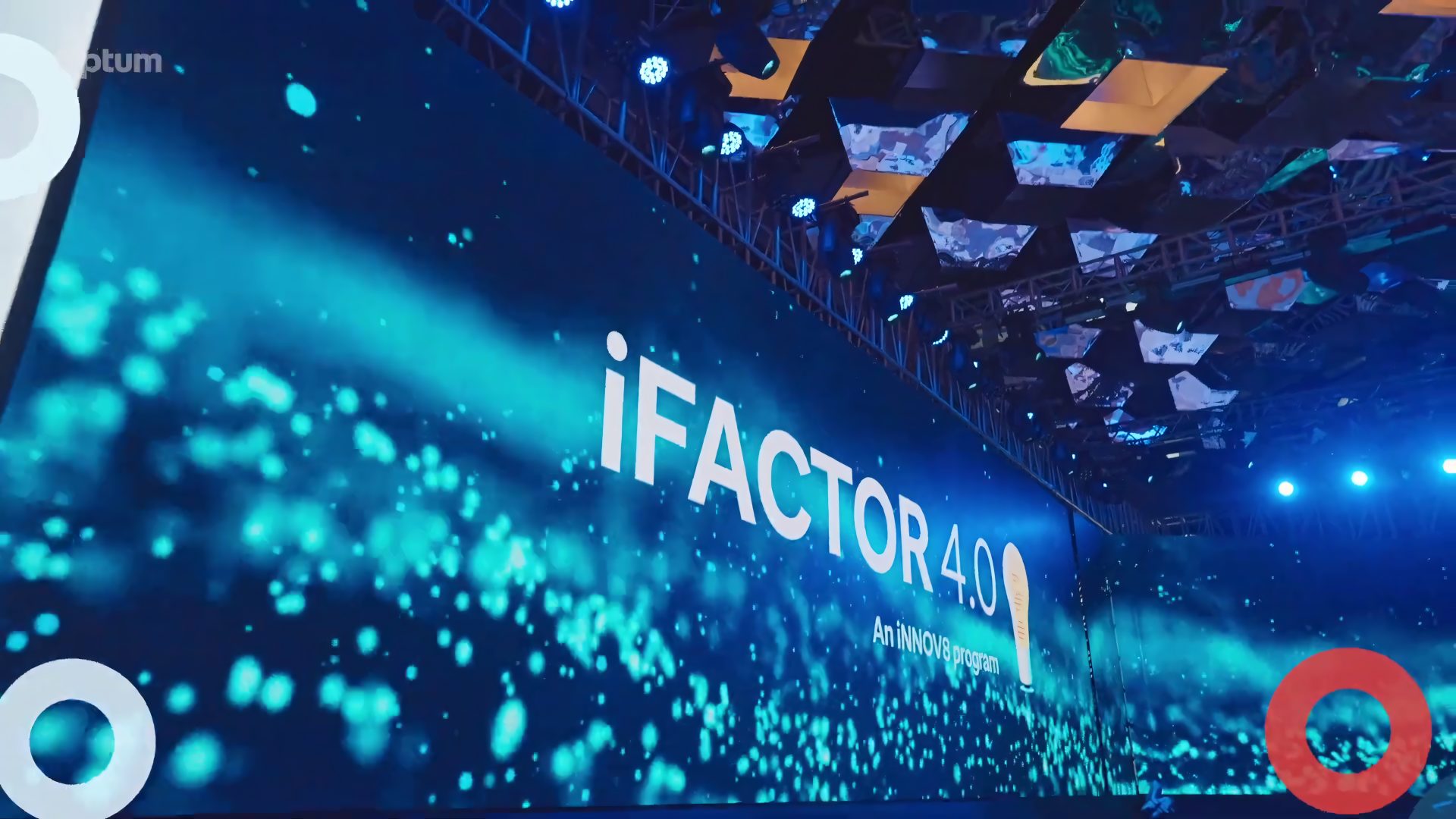 Immersive teal LED environment carrying the iFactor 4.0 identity above a full audience at Optum’s innovation summit