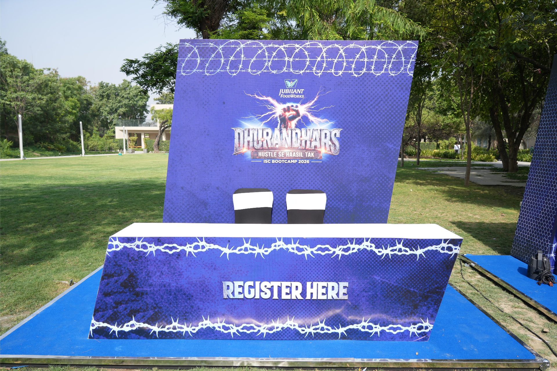 Branded outdoor registration desk under the Dhurandhars ISC Bootcamp 2026 backdrop